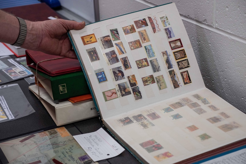 An opened stamp album, with a hand holding it open