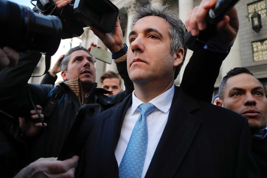 Former Trump lawyer Michael Cohen walks out of a US federal court in a throng of reporters