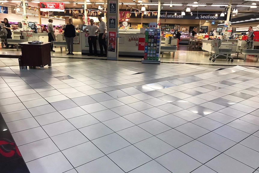 Tiles buckling along lines on the floor outside a Coles supermarket