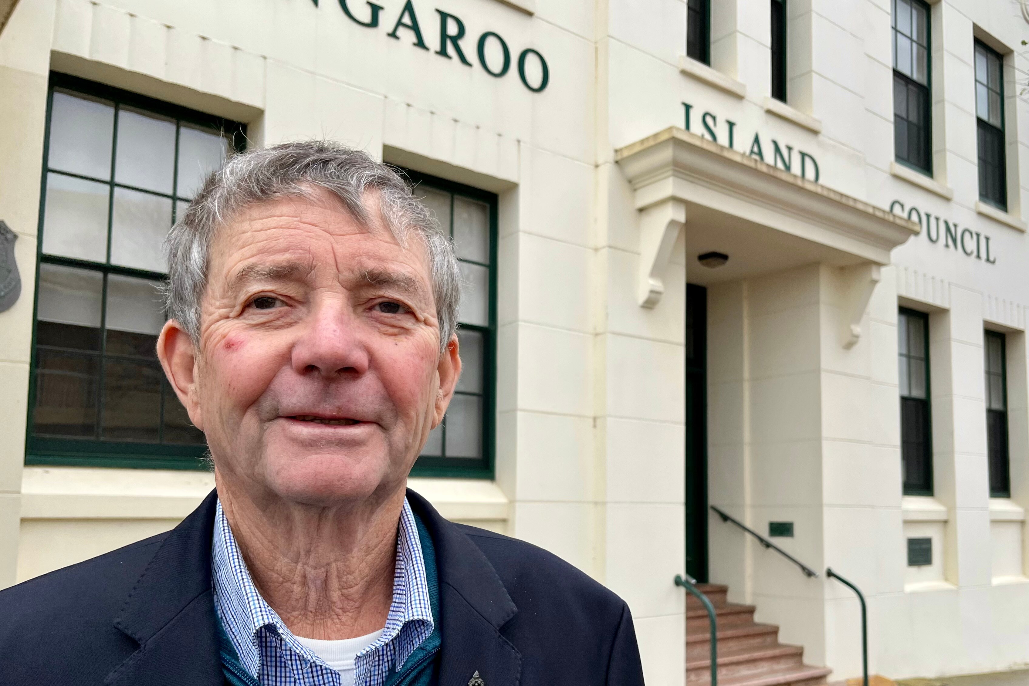 A man standing outside the Kangaroo Island Council building, cream coloured. 