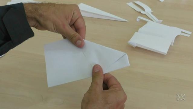 Hands fold paper plane