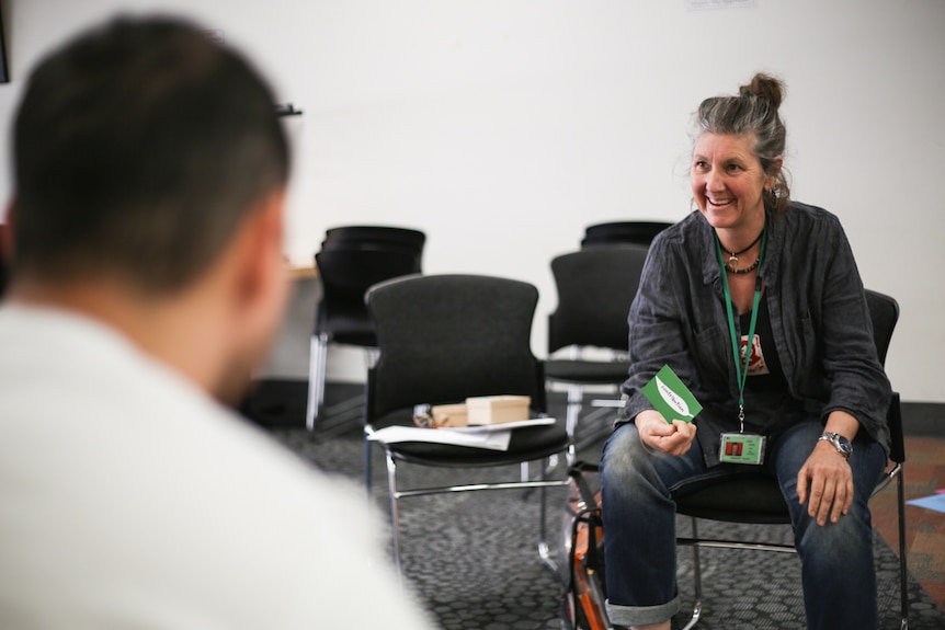 Co-facilitator Lucy Young holding a card with the back of a prisoner's head in the left hand corner of the frame.