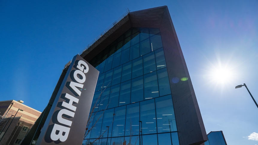 A close-up shot of a big glass building with the sign 'GovHub' out the front. Blue sunny sky in background.