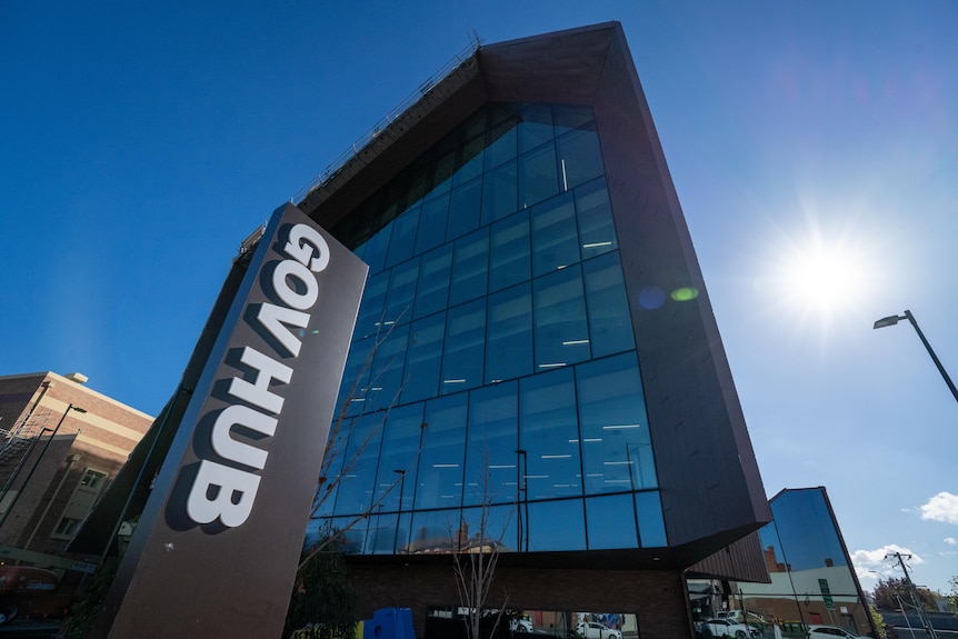 A close-up shot of a big glass building with the sign 'GovHub' out the front. Blue sunny sky in background.