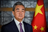 Chinese Foreign Minister Wang Yi stands in front of a Chinese flag