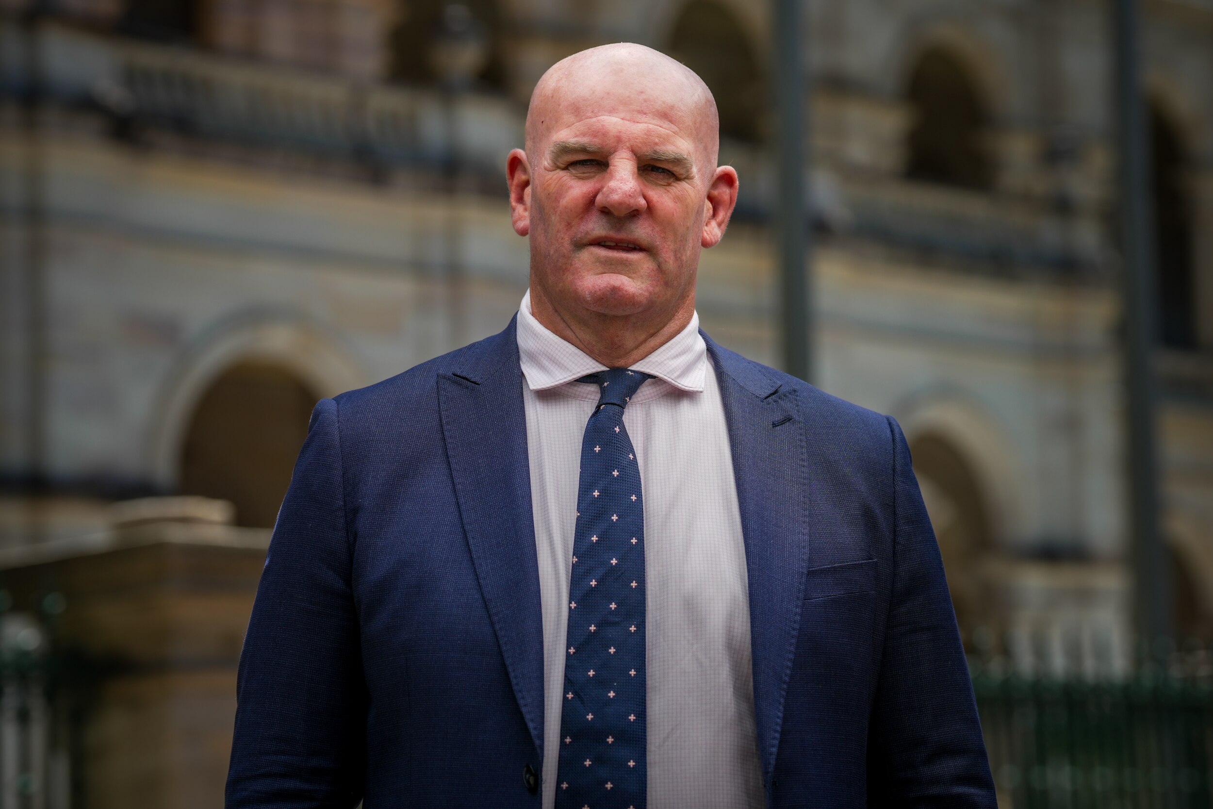 A man stands in a city street wearing a suit and tie.