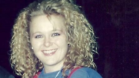 A young Suzi Dent wearing a baggy blue top and red braces holding up her jeans