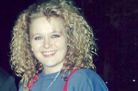 A young Suzi Dent wearing a baggy blue top and red braces holding up her jeans