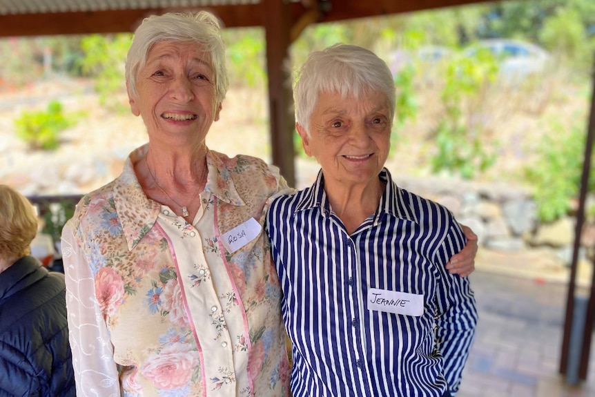 Two women in their 70s stand smiling