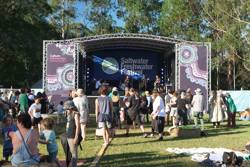 Stage decorated with aboriginal art and crowd gathered on grass