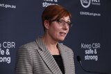 A woman with short red hair stands at a lectern
