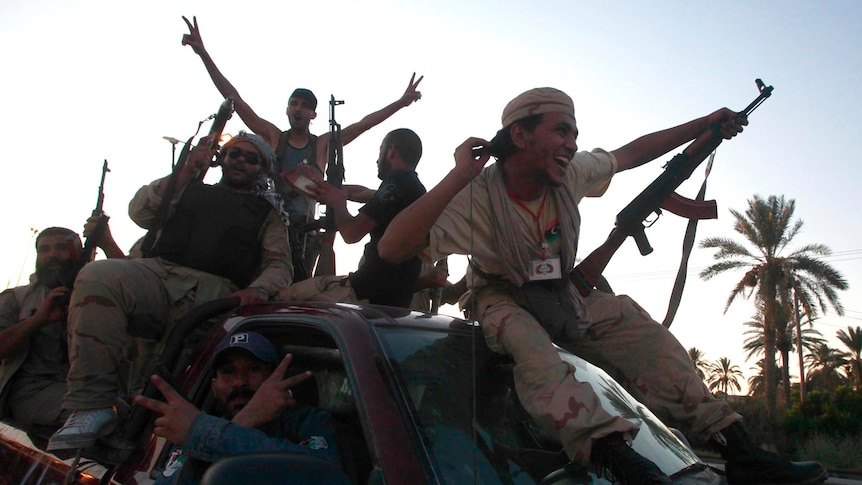 Libyan rebels ride through the town of Maia giving V-for victory sign