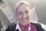 A selfie of Louise smiling wearing Qantas uniform in the doorway of a plane.
