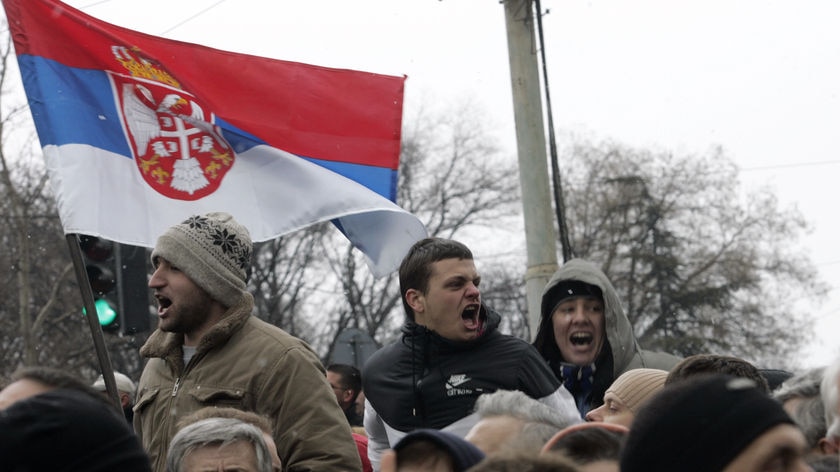 Protesters wave a Serbian flag and shout slogans during a rally in Belgrade