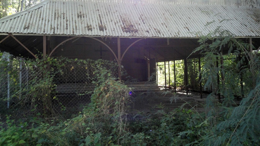 The cross in the open walled church can be seen through overgrowth at Oombulgurri