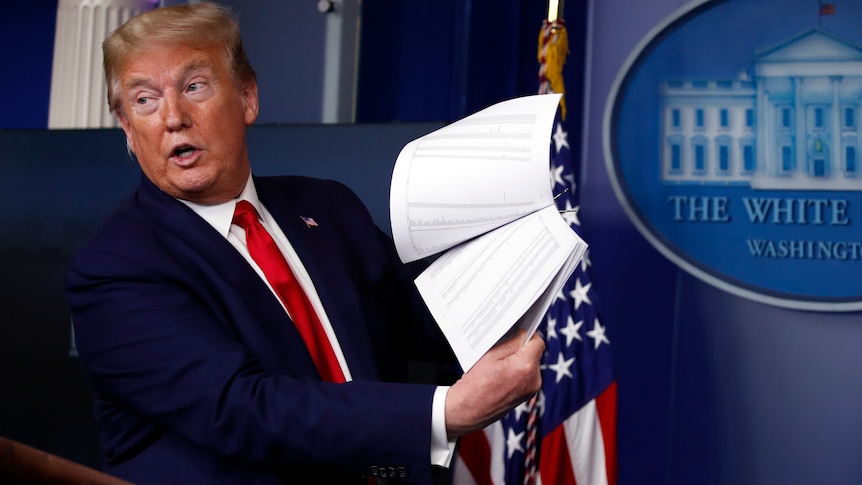 Donald Trump holds up papers as he speaks in the James Brady Press Briefing Room of the White House