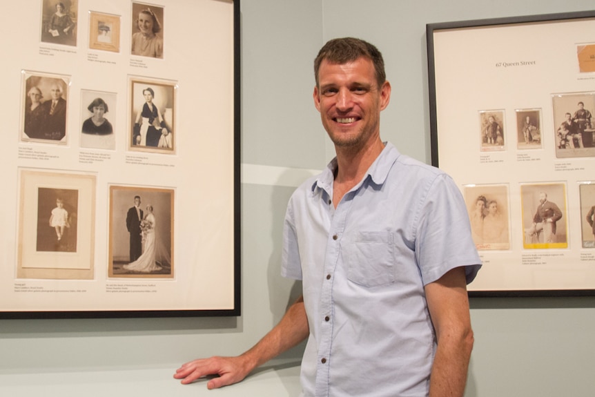 Curator Phil Manning stands with photos as part of the exhibition.