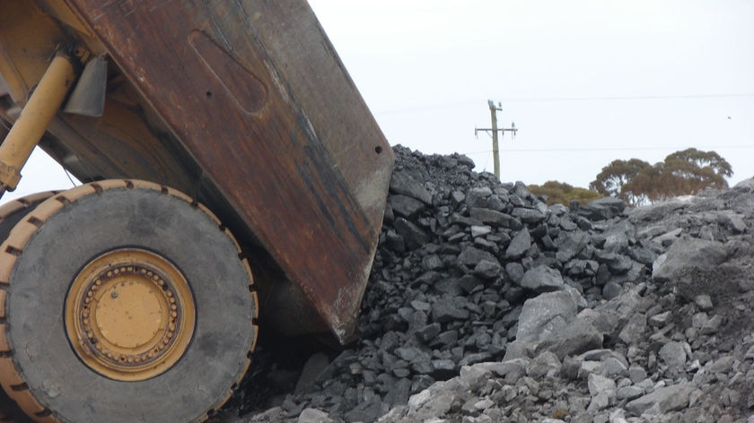 Rear of dump truck tipped up dropping rocks, nickel ore, on the ground