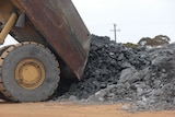 Rear of dump truck tipped up dropping rocks, nickel ore, on the ground