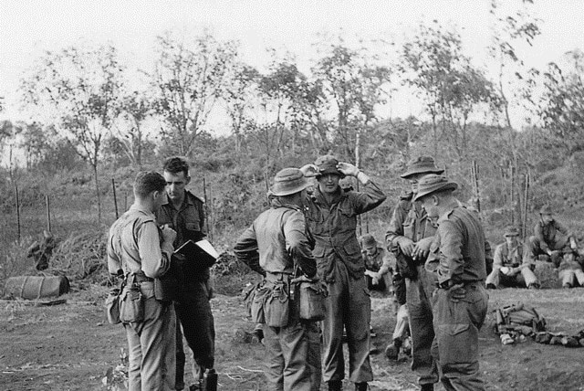 Tim Fischer stands with a group of men in army uniform.