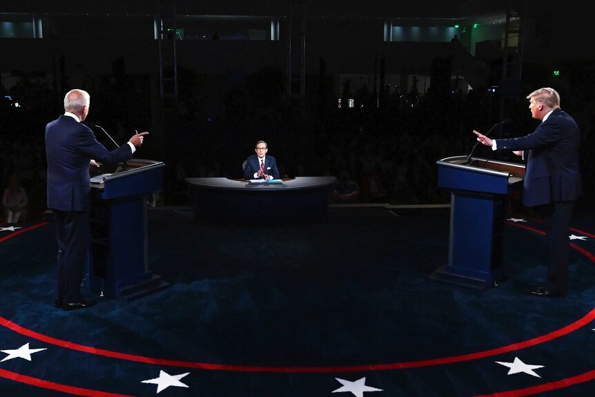 Mr Trump and Mr Biden both point fingers as they stand on a platform during the first debate.