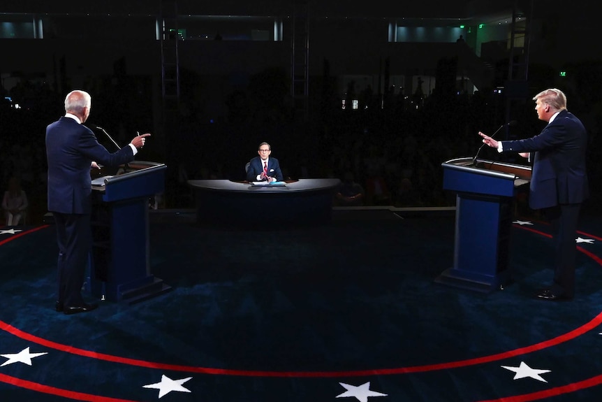 Mr Trump and Mr Biden both point fingers as they stand on a platform during the first debate.