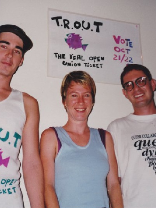 An old photo of people smiling with a sign that reads TROUT