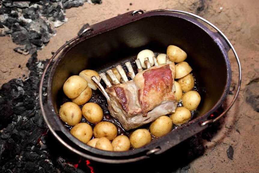 a rack of goat in a camp oven surrounded by potatoes