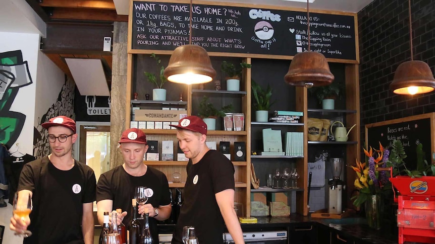 Three men stand behind a restaurant counter.