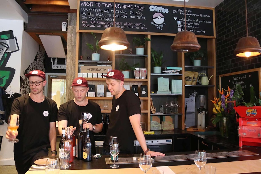 Three men stand behind a restaurant counter.