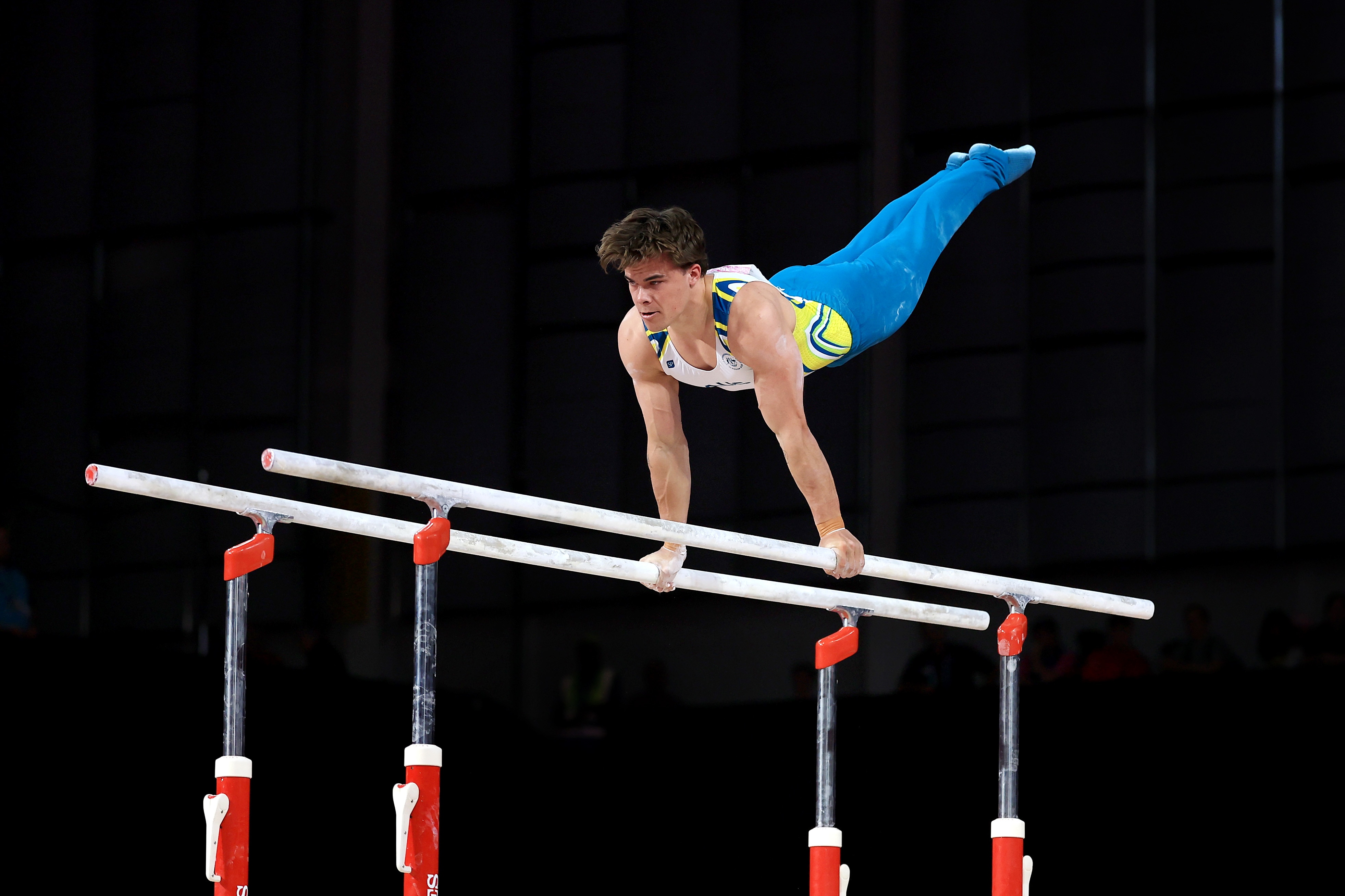 Jesse Moore holds on to two bars as he holds himself in the air mid-routine.