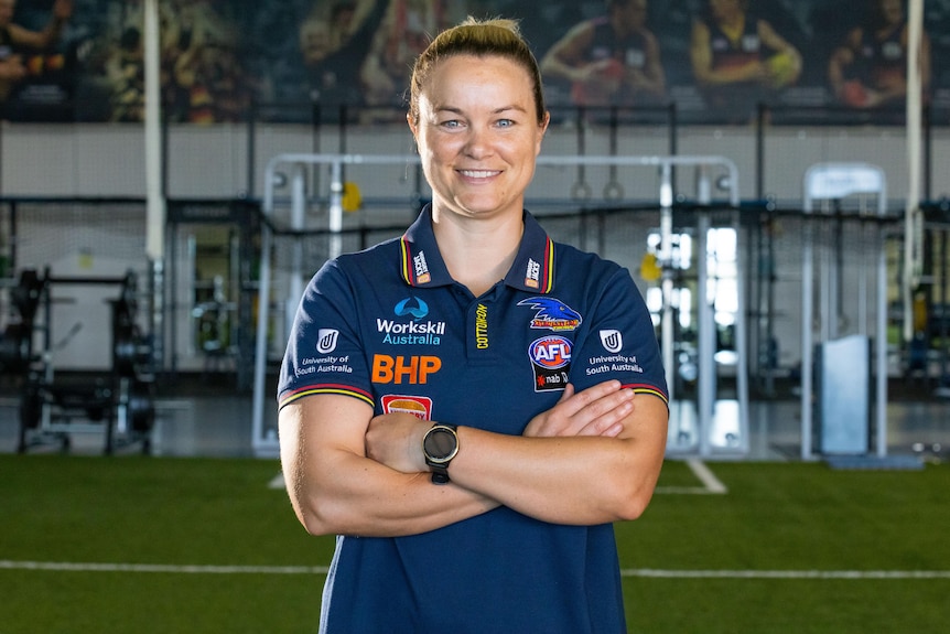 Courtney Cramey folds her arms and smiles while standing in a gym.