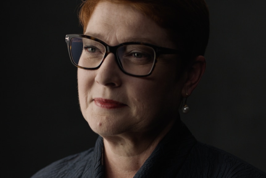 A portrait of a women in black wearing glasses, glancing to her right