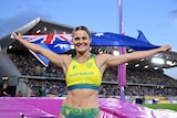 A woman smiles as she holds an Australian flag.