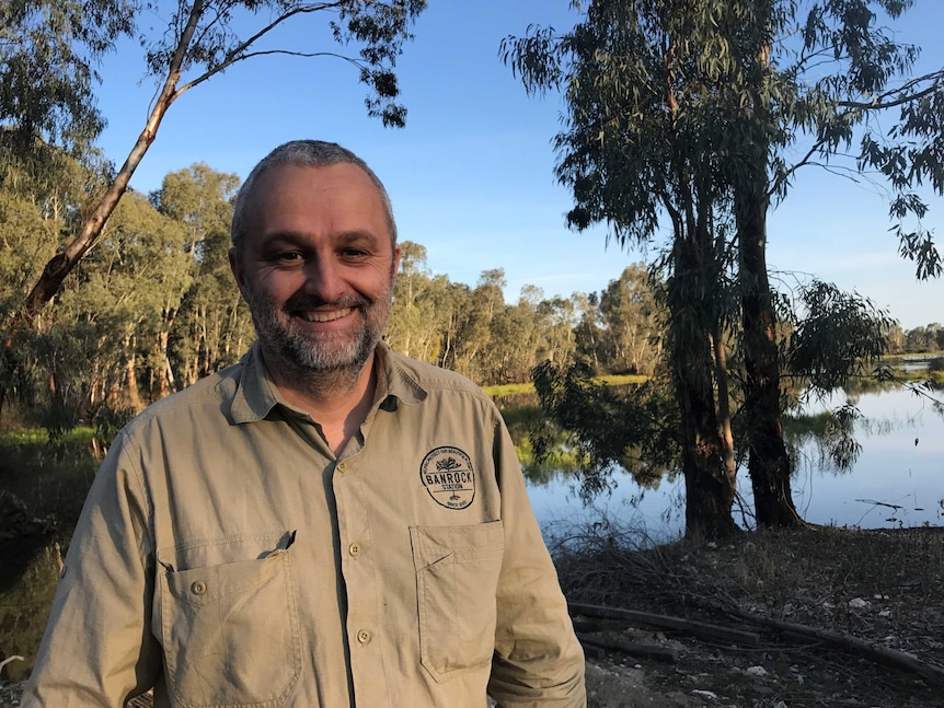 Man stands in front of floodplain smiling