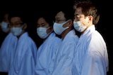Men wearing white shirts and light blue wraps and medical masks.
