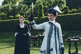Colour still of Emma Stone and Rachel Weisz standing on lawn in 2018 film The Favourite.