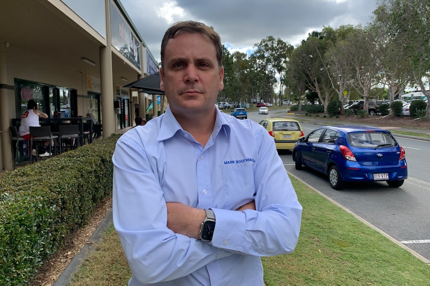 Mark Boothman wears a blue button-up shirt with his arms crossed.