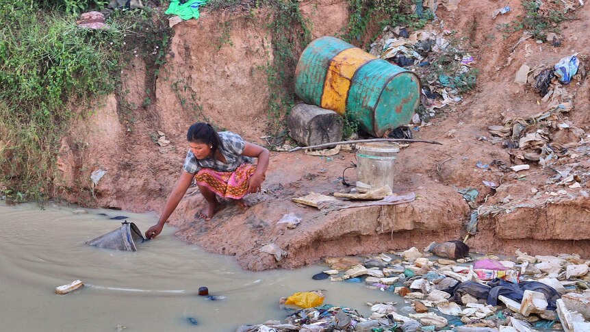 A woman fetches water at a Cambodian rubbish dump