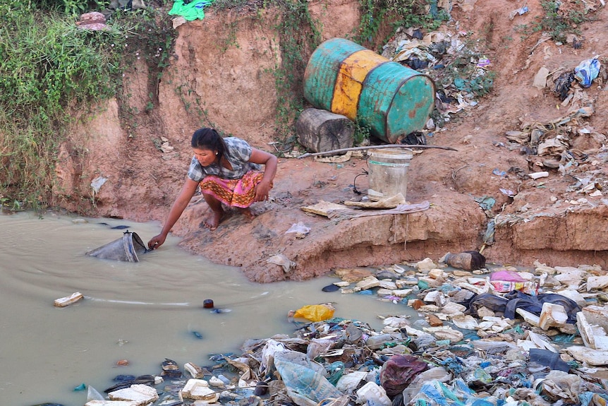 A woman fetches water at a Cambodian rubbish dump