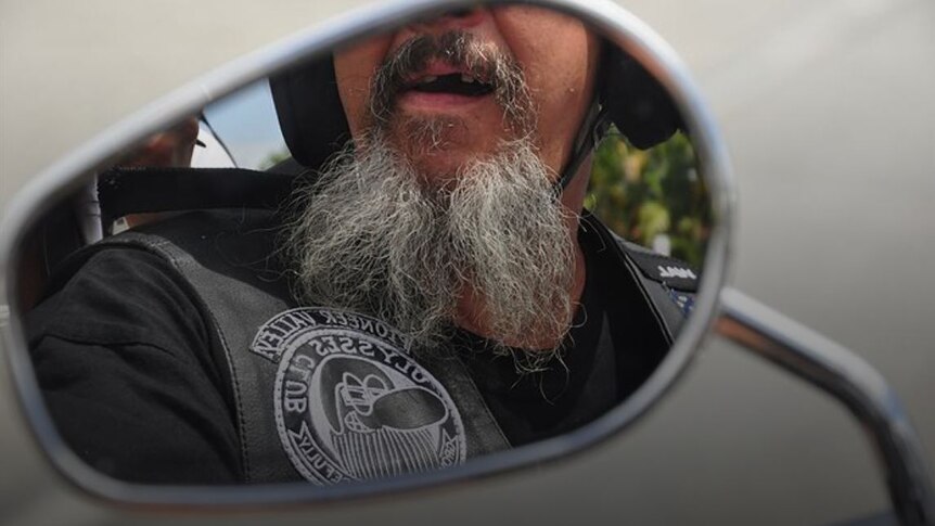 Man with a beard reflection in a motorcycle mirror