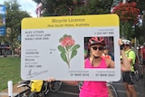 A cyclist holding up a mock bicycle licence at a protest against proposed New South Wales traffic laws.