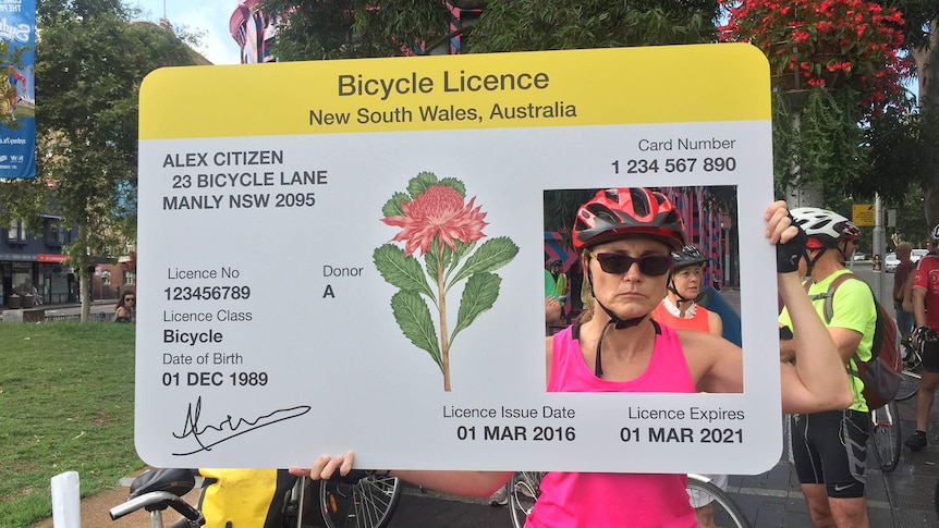 A cyclist holding up a mock bicycle licence at a protest against proposed New South Wales traffic laws.