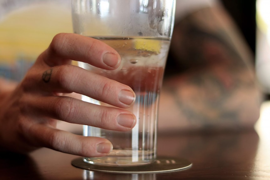 Close-up of person holding carbonated drink with lemon segment