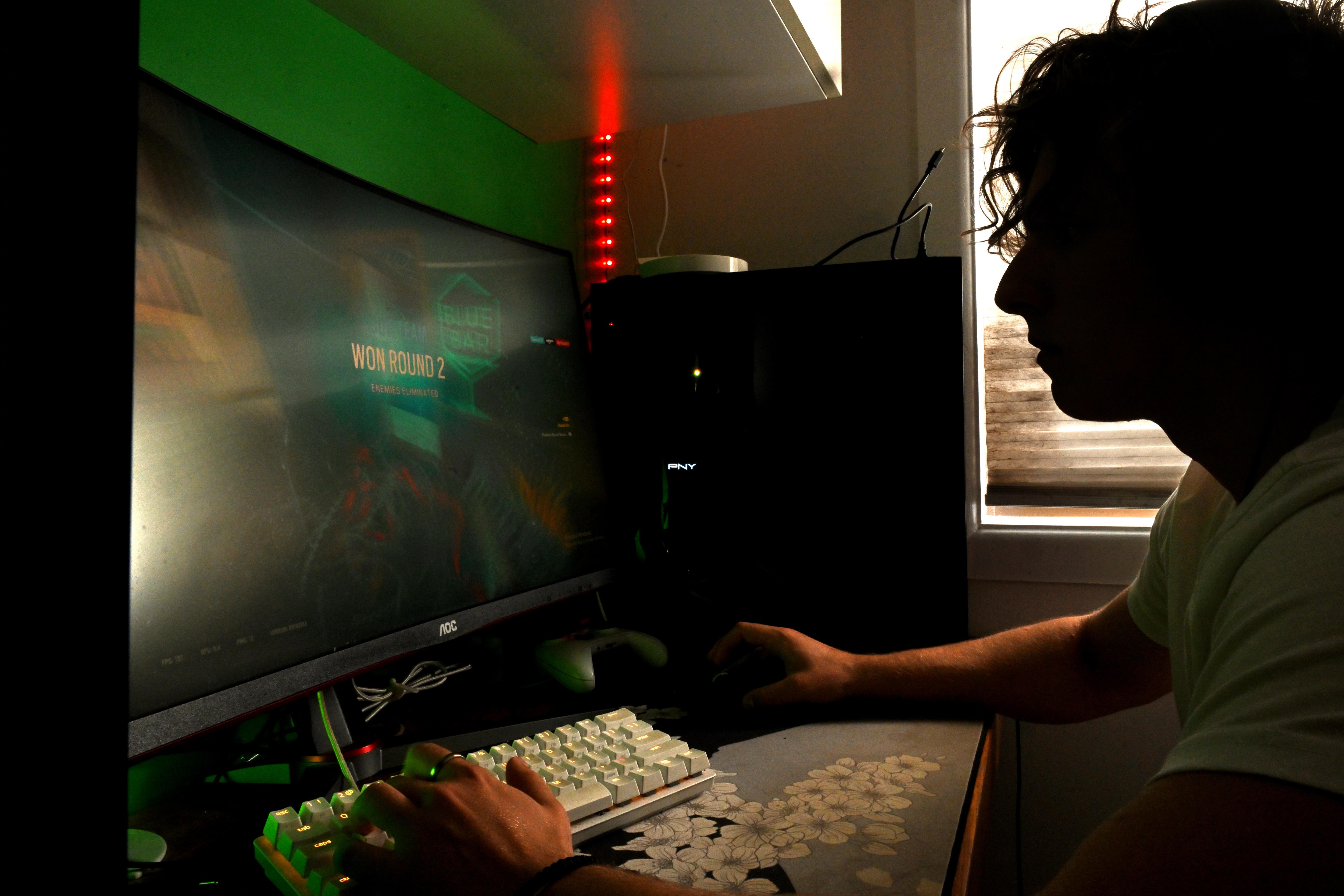 Online gamers play in their gaming room with a screen and keyboard visible.