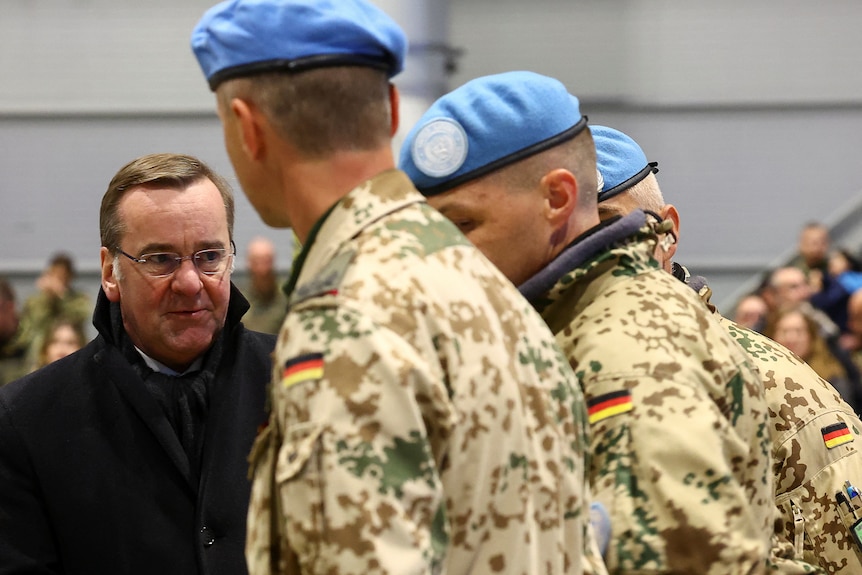 United Nations soldiers stands next to German Defence Minister 