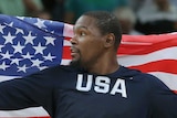 Kevin Durant looks to his right as he holds the United States flag behind his back during a basketball game