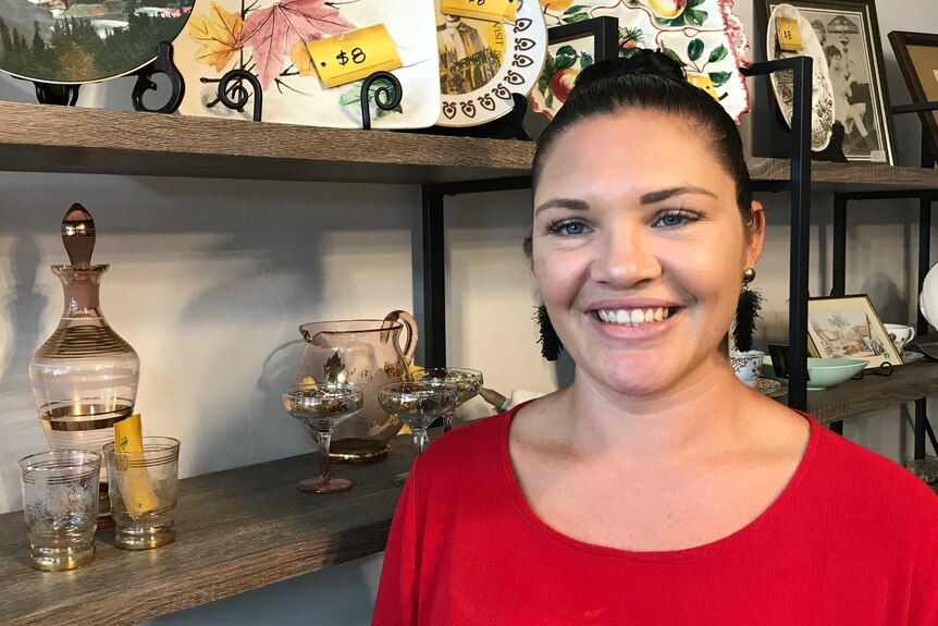 A woman standing in front of a shelf of vintage homewares.