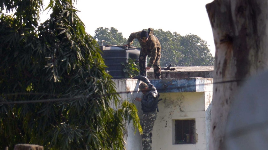 Indian security personnel position themselves on a rooftop