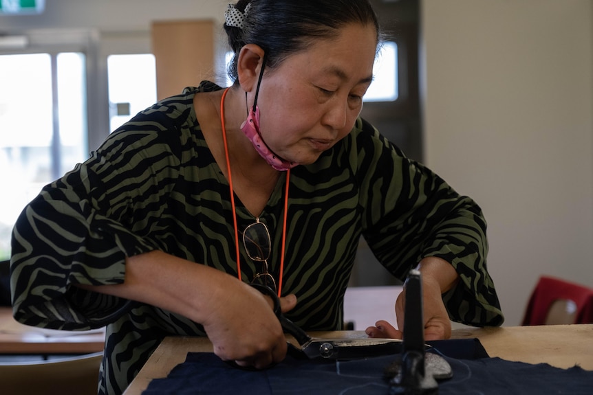 K'Yo cuts fabric on a cutting table.